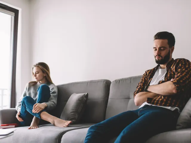 Un couple distant sur leur canapé pensant à la séparation et au divorce.