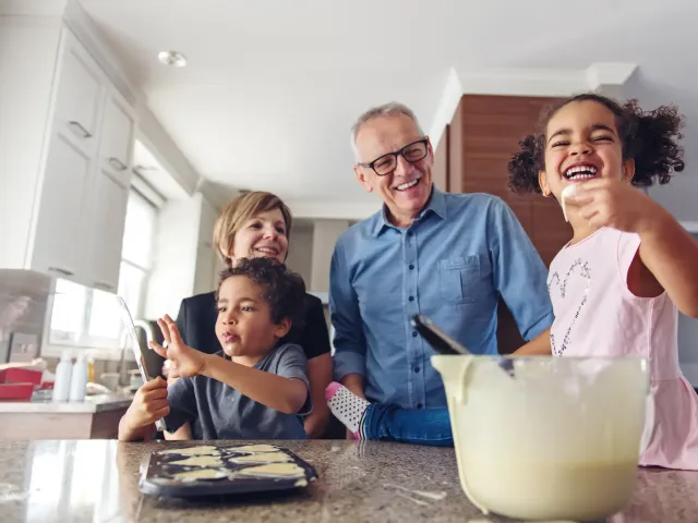 Des grands-parents et leurs petits-enfant font des gâteaux dans leur cuisine.