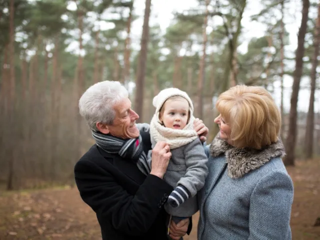 un couple de grands-parents tient un bébé dans leur bras.