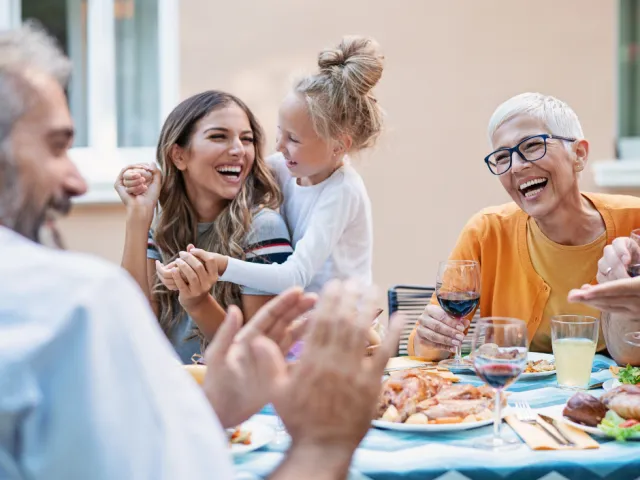 Une famille heureuse mange à table après avoir rédigé un mandat extrajudiciaire pour anticiper leur avenir.