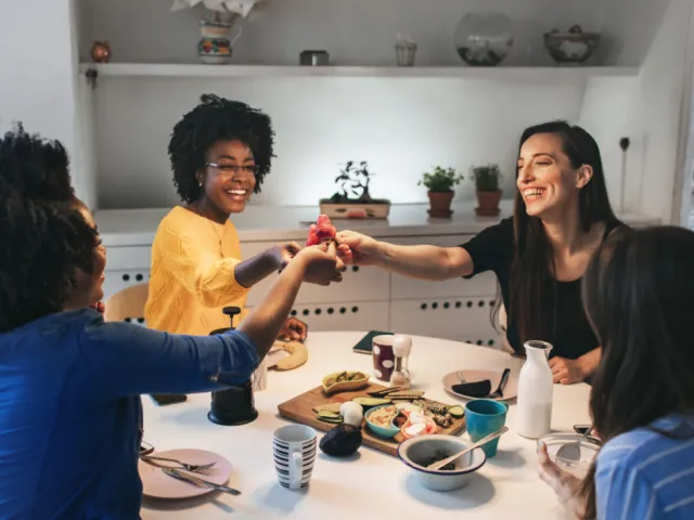 Quatre colocataires en Belgique profitent d'un bon repas tous ensemble après avoir rédigé un pacte de colocation clair pour éviter tout conflit.
